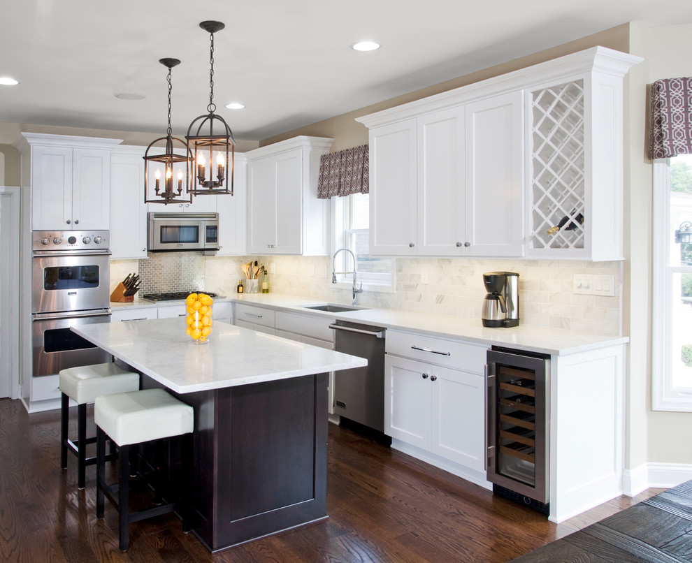 Inspiration for a mid-sized transitional l-shaped eat-in kitchen in Philadelphia with a single-bowl sink, shaker cabinets, white cabinets, marble benchtops, white splashback, stone tile splashback, stainless steel appliances, dark hardwood floors and with island.