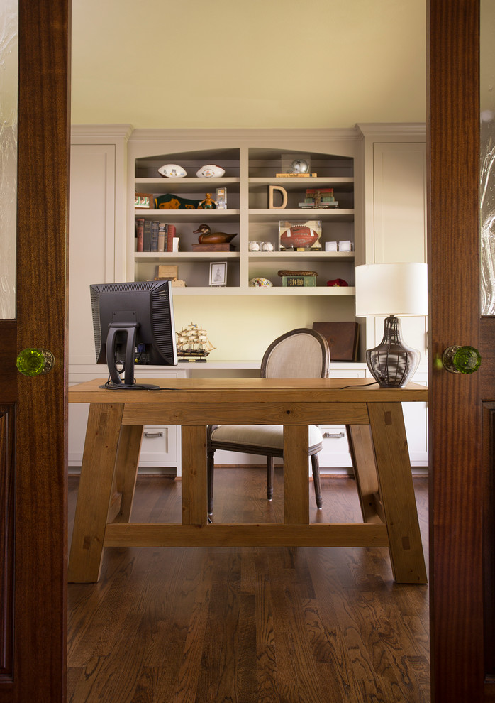 Traditional home office in Dallas with beige walls, dark hardwood floors and a freestanding desk.