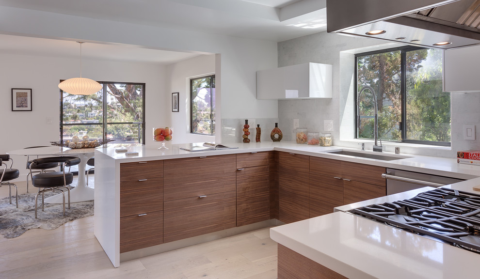 Inspiration for a contemporary u-shaped open plan kitchen in Other with a double-bowl sink, flat-panel cabinets, light wood cabinets, quartz benchtops, white splashback, stainless steel appliances, a peninsula, stone slab splashback, porcelain floors and white benchtop.