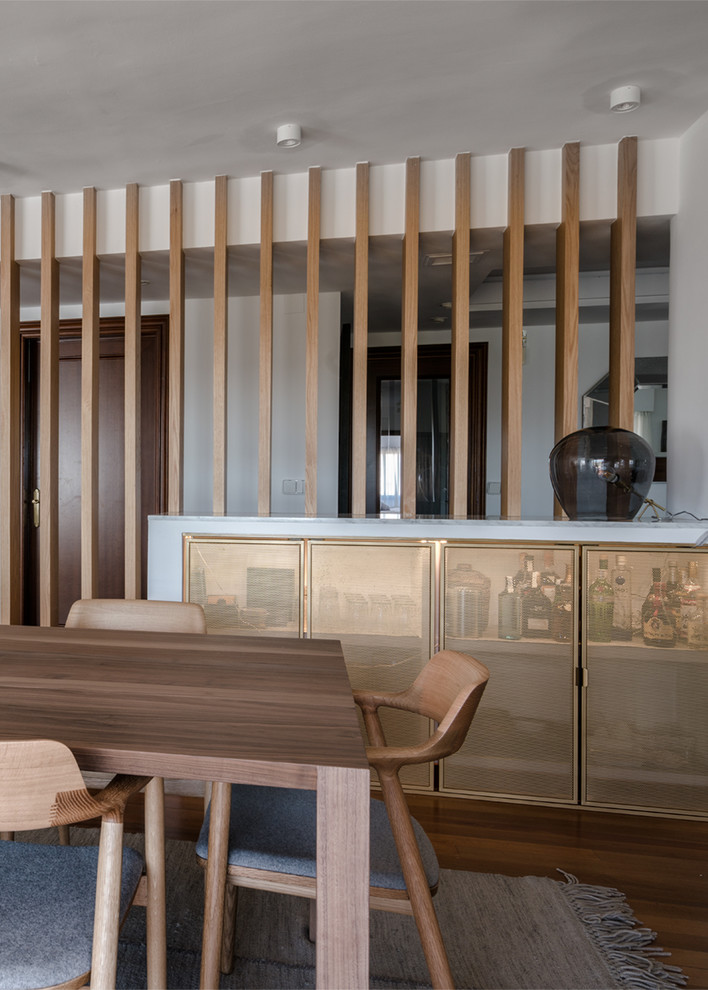 Diseño de comedor nórdico grande abierto con paredes blancas, suelo de madera oscura y suelo marrón