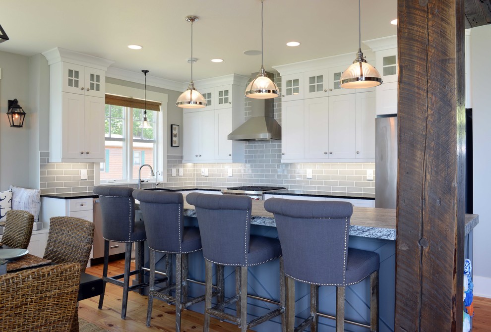 Inspiration for a mid-sized transitional l-shaped eat-in kitchen in Other with shaker cabinets, white cabinets, granite benchtops, grey splashback, subway tile splashback, stainless steel appliances, light hardwood floors, with island and an undermount sink.