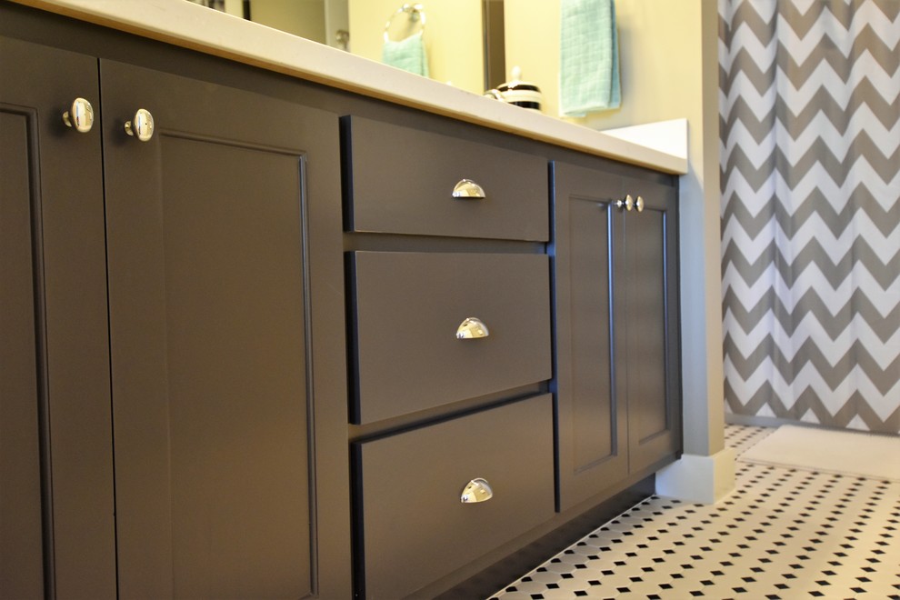 This is an example of a mid-sized arts and crafts kids bathroom in Kansas City with flat-panel cabinets, brown cabinets, an alcove tub, a shower/bathtub combo, a one-piece toilet, black and white tile, mosaic tile, grey walls, porcelain floors, an integrated sink and solid surface benchtops.
