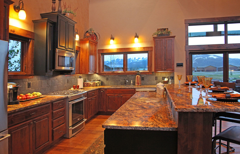 Open concept kitchen - large rustic l-shaped medium tone wood floor and brown floor open concept kitchen idea with medium tone wood cabinets, granite countertops, gray backsplash, stainless steel appliances, an undermount sink, raised-panel cabinets, ceramic backsplash and an island
