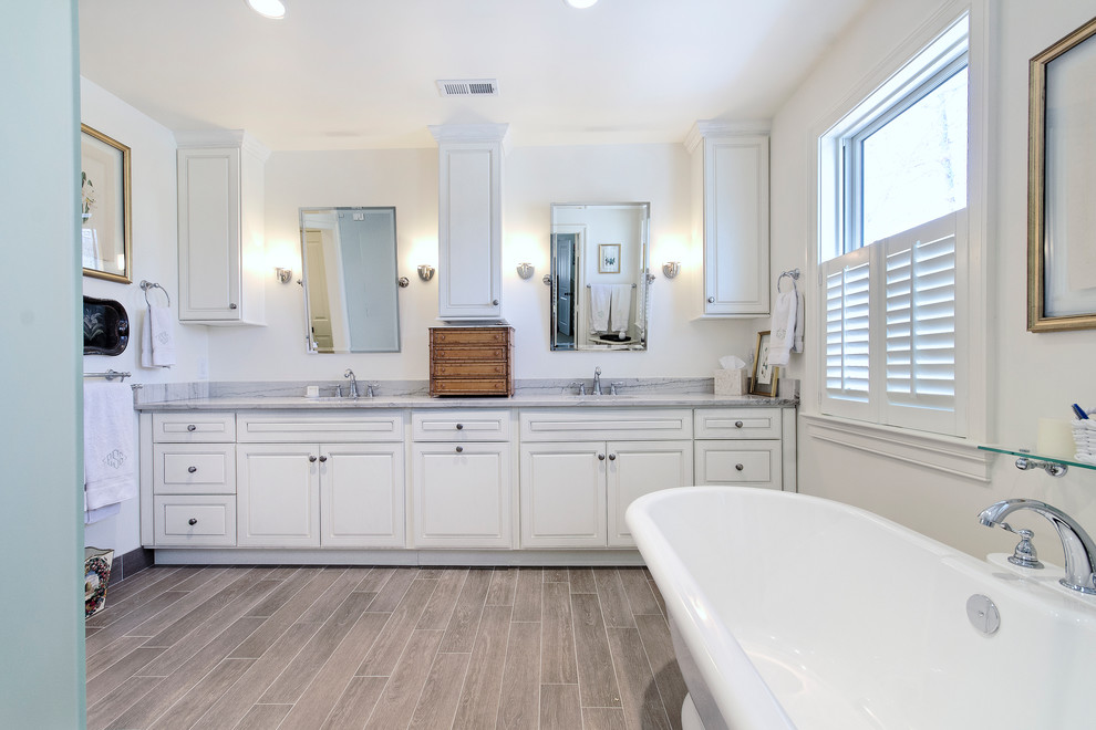 Freestanding bathtub - transitional beige tile and ceramic tile freestanding bathtub idea with an undermount sink, raised-panel cabinets, white cabinets, marble countertops and a two-piece toilet