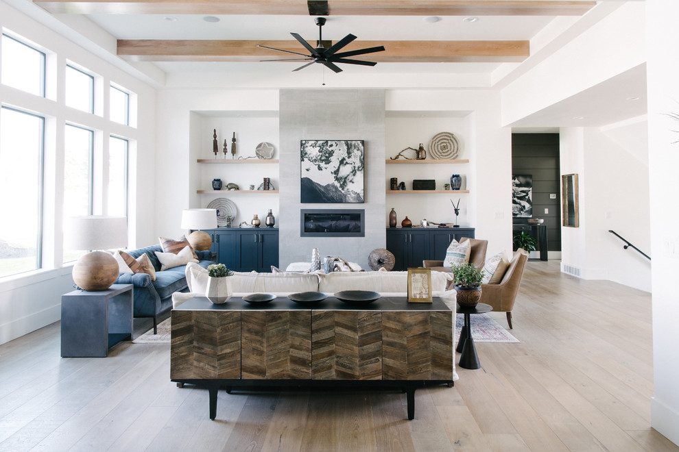 This is an example of a large transitional open concept living room in Salt Lake City with white walls, a ribbon fireplace, a concrete fireplace surround, no tv, light hardwood floors and beige floor.