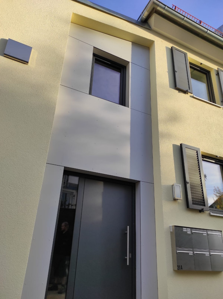 Großes, Zweistöckiges Wohnung mit Putzfassade, gelber Fassadenfarbe, Walmdach, Ziegeldach und rotem Dach in München