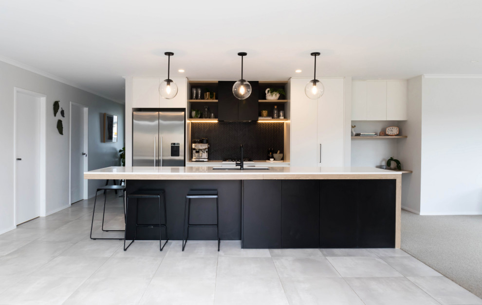 Inspiration for a large contemporary galley kitchen in Auckland with an undermount sink, flat-panel cabinets, white cabinets, black splashback, stainless steel appliances, with island, grey floor and white benchtop.