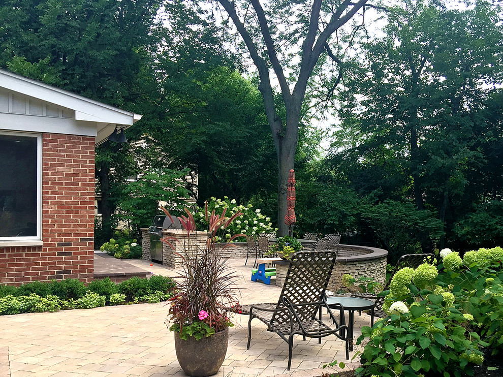 Traditional backyard patio in Chicago with an outdoor kitchen, concrete pavers and no cover.