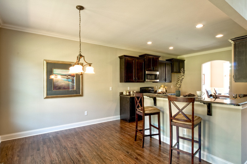 Transitional l-shaped dark wood floor eat-in kitchen photo with an undermount sink, flat-panel cabinets, dark wood cabinets, granite countertops and stainless steel appliances