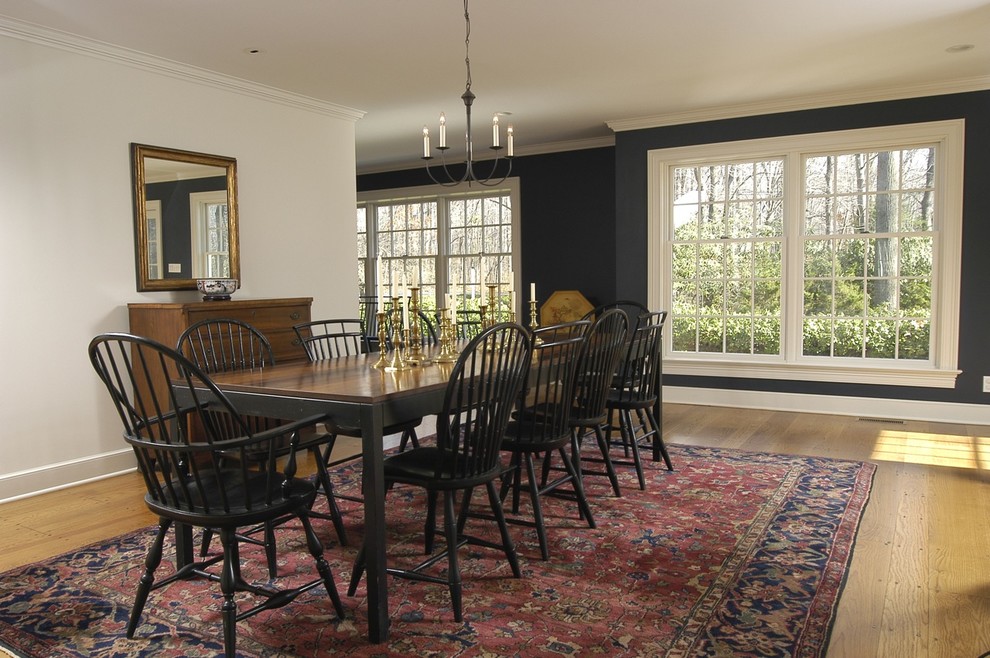 Design ideas for a large traditional dining room in New York with black walls, medium hardwood floors, no fireplace and brown floor.