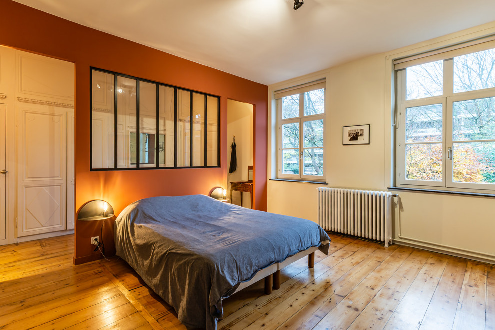 パリにある広いモダンスタイルのおしゃれな主寝室 (赤い壁、無垢フローリング、暖炉なし、茶色い床) のインテリア