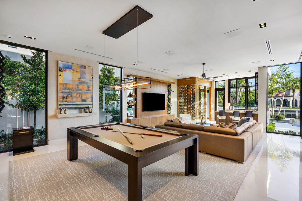 This is an example of a large contemporary open concept family room in Miami with a game room, beige walls, marble floors, a wall-mounted tv and white floor.
