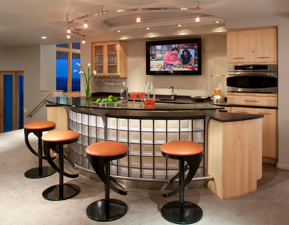 This is an example of an expansive contemporary u-shaped seated home bar in Denver with carpet, flat-panel cabinets, light wood cabinets, an undermount sink, beige floor and black benchtop.