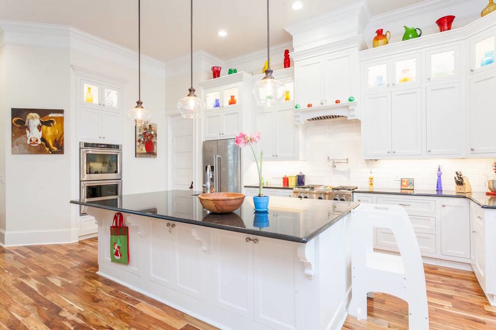 Inspiration for a large transitional u-shaped medium tone wood floor and multicolored floor open concept kitchen remodel with a farmhouse sink, recessed-panel cabinets, white cabinets, quartz countertops, white backsplash, subway tile backsplash, stainless steel appliances, an island and black countertops
