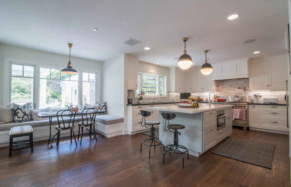 This is an example of a large transitional u-shaped eat-in kitchen in Los Angeles with an undermount sink, recessed-panel cabinets, white cabinets, grey splashback, stone tile splashback, stainless steel appliances, medium hardwood floors and with island.