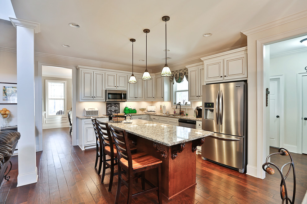 Design ideas for a mid-sized country l-shaped open plan kitchen in Atlanta with an undermount sink, raised-panel cabinets, white cabinets, granite benchtops, white splashback, stainless steel appliances, medium hardwood floors, with island and brown floor.