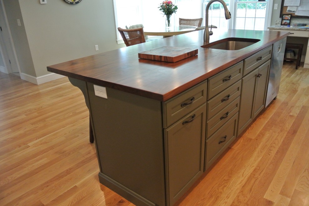 Inspiration for a transitional galley light wood floor eat-in kitchen remodel in Boston with an undermount sink, stainless steel appliances, an island, shaker cabinets, white cabinets, wood countertops, white backsplash, ceramic backsplash and brown countertops