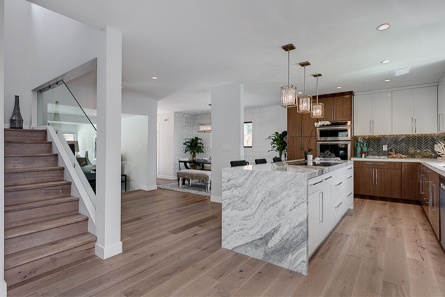 Design ideas for a mid-sized modern l-shaped eat-in kitchen in Los Angeles with an undermount sink, flat-panel cabinets, dark wood cabinets, marble benchtops, grey splashback, matchstick tile splashback, stainless steel appliances, with island and light hardwood floors.