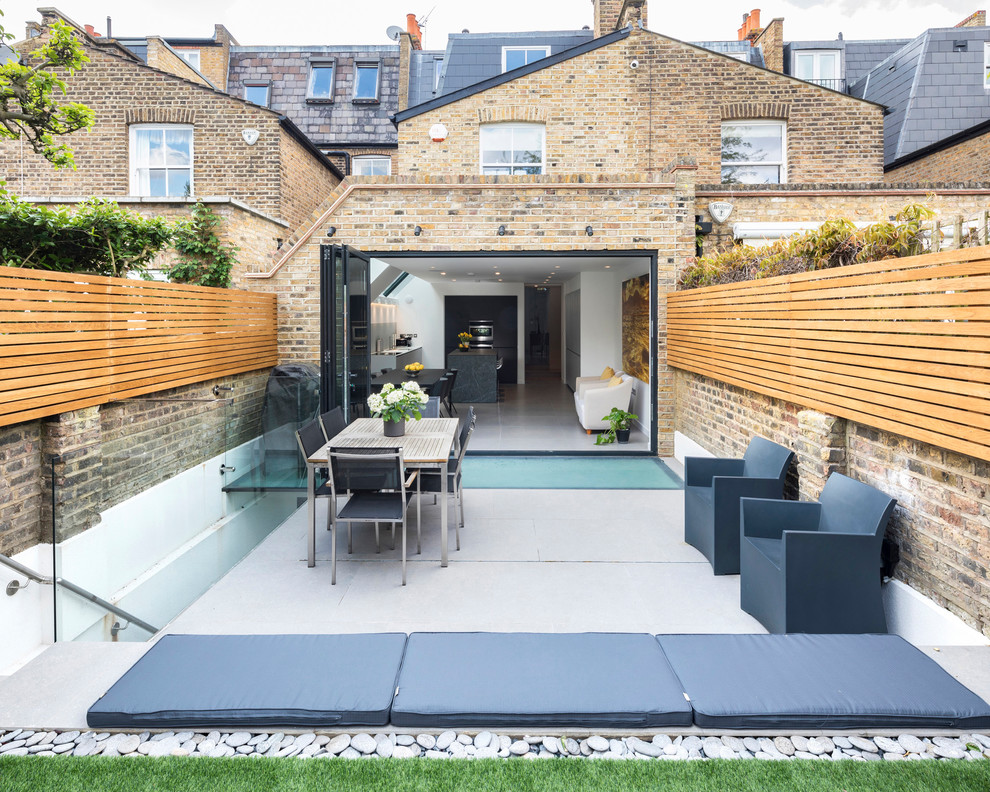 Contemporary backyard patio in London with concrete slab and no cover.
