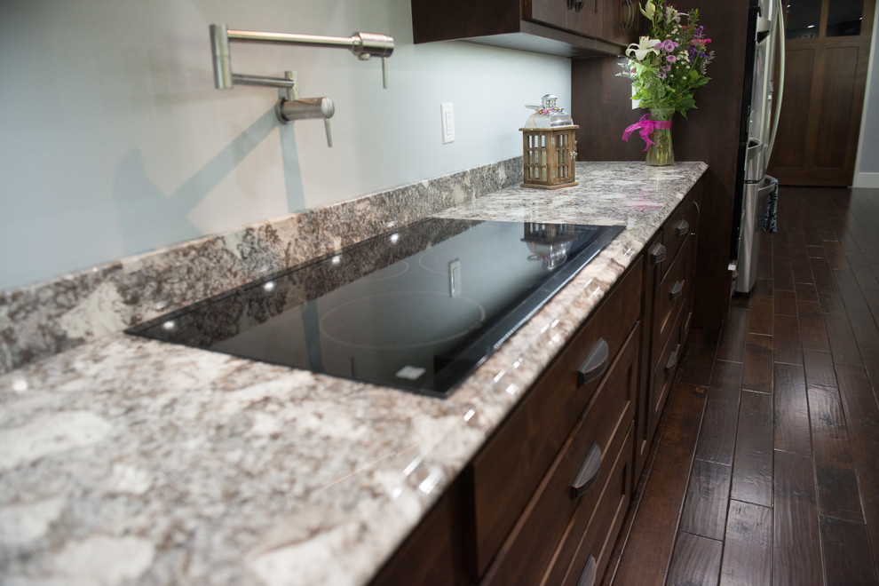 Inspiration for a transitional l-shaped open concept kitchen remodel with an undermount sink, shaker cabinets, dark wood cabinets, granite countertops, stainless steel appliances, an island and multicolored countertops
