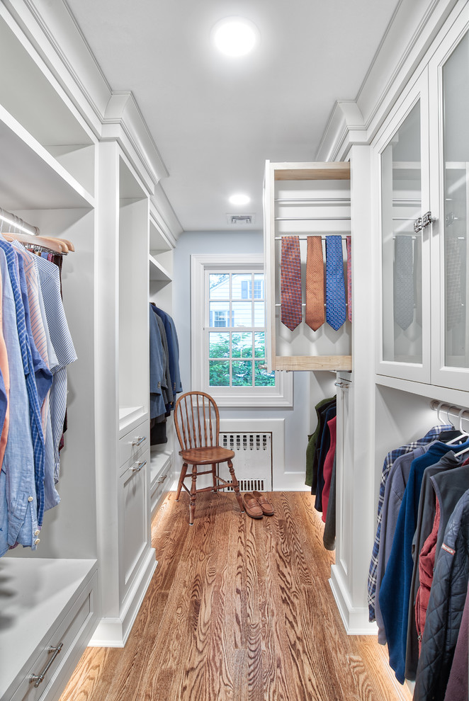 Traditional men's walk-in wardrobe in New York with white cabinets and medium hardwood floors.