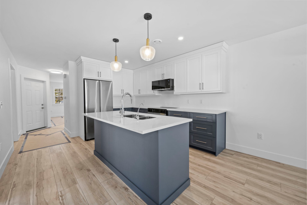 Transitional l-shaped vinyl floor and brown floor open concept kitchen photo with shaker cabinets, gray cabinets, quartz countertops, stainless steel appliances, an island and white countertops