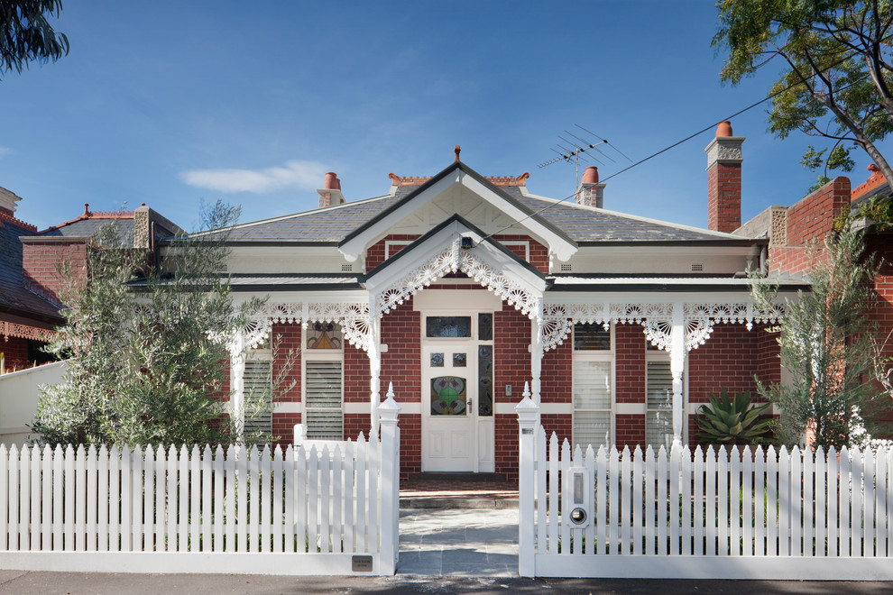 This is an example of a mid-sized traditional two-storey brick red house exterior in Melbourne with a hip roof and a mixed roof.