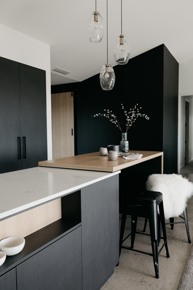 Photo of a large contemporary galley eat-in kitchen in Other with an undermount sink, flat-panel cabinets, black cabinets, quartz benchtops, window splashback, black appliances, concrete floors, with island, grey floor and white benchtop.