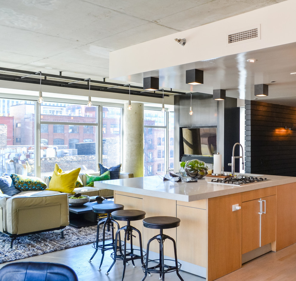 Inspiration for a large industrial galley open plan kitchen in Chicago with an undermount sink, flat-panel cabinets, marble benchtops, stainless steel appliances, with island, light wood cabinets and light hardwood floors.
