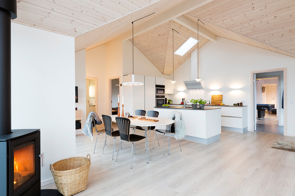 Inspiration for a mid-sized contemporary l-shaped eat-in kitchen in Aarhus with with island, flat-panel cabinets, white cabinets, stainless steel appliances, light hardwood floors, a drop-in sink, granite benchtops and white splashback.