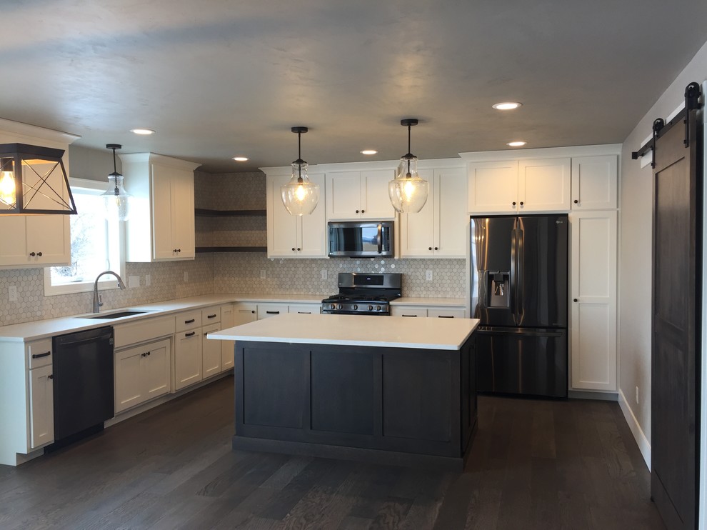 Example of a transitional l-shaped dark wood floor and brown floor eat-in kitchen design with an undermount sink, shaker cabinets, white cabinets, quartz countertops, white backsplash and an island