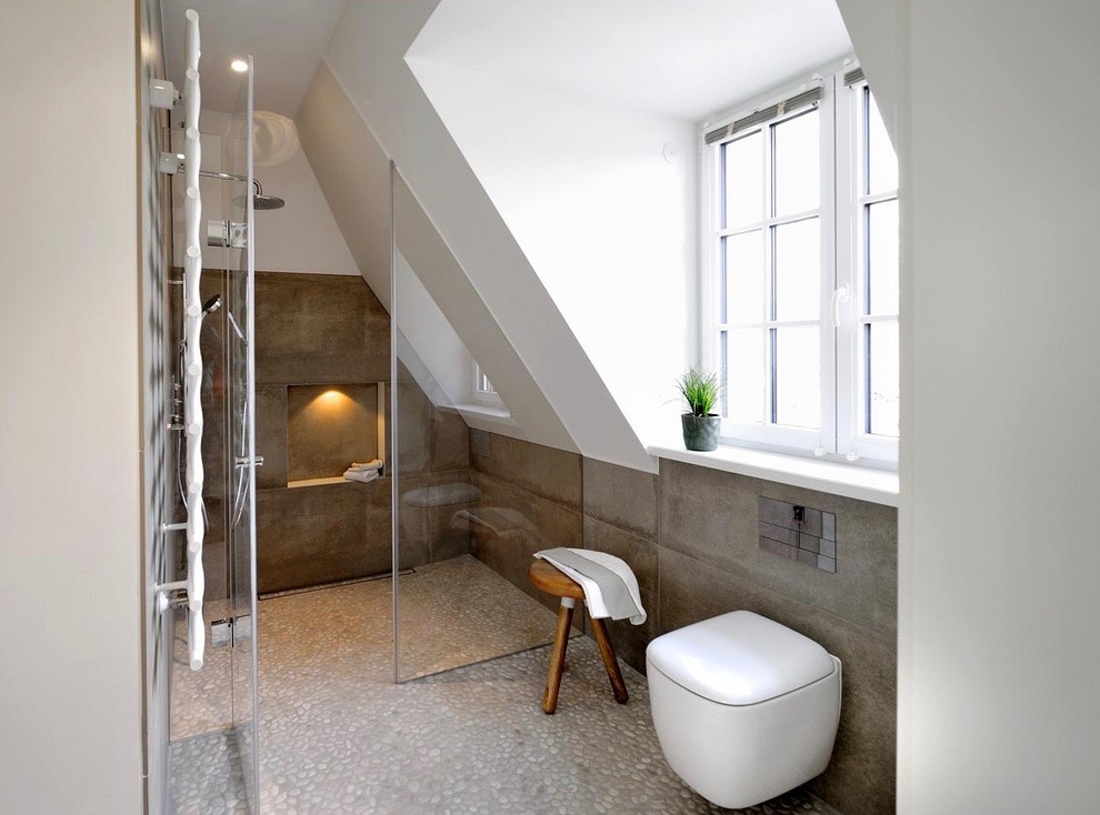 Photo of a large modern 3/4 bathroom in Munich with white cabinets, a curbless shower, a wall-mount toilet, gray tile, white walls, a trough sink, flat-panel cabinets, stone tile, pebble tile floors, wood benchtops and beige floor.