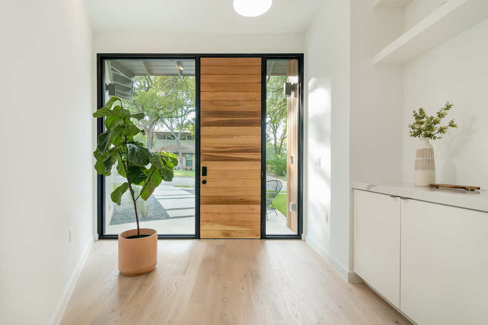 Inspiration for a mid-sized scandinavian front door in Austin with white walls, light hardwood floors, a single front door, a light wood front door and brown floor.