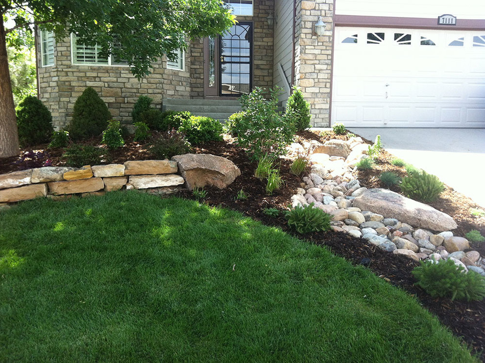 Inspiration for a mid-sized traditional front yard driveway in Denver with a retaining wall and mulch.