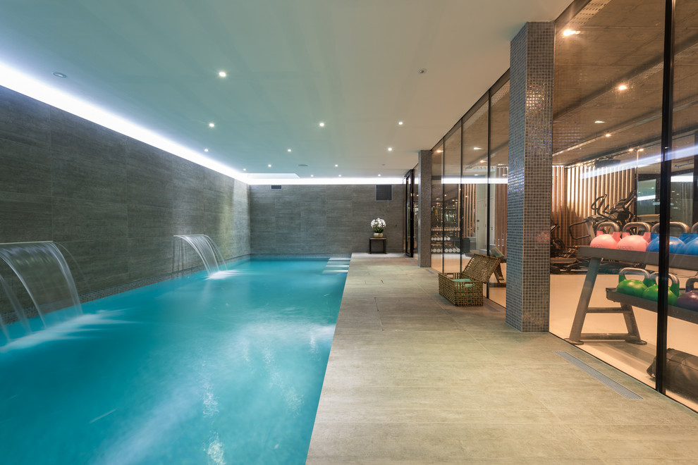 Inspiration for a contemporary indoor rectangular lap pool in London with a water feature and tile.