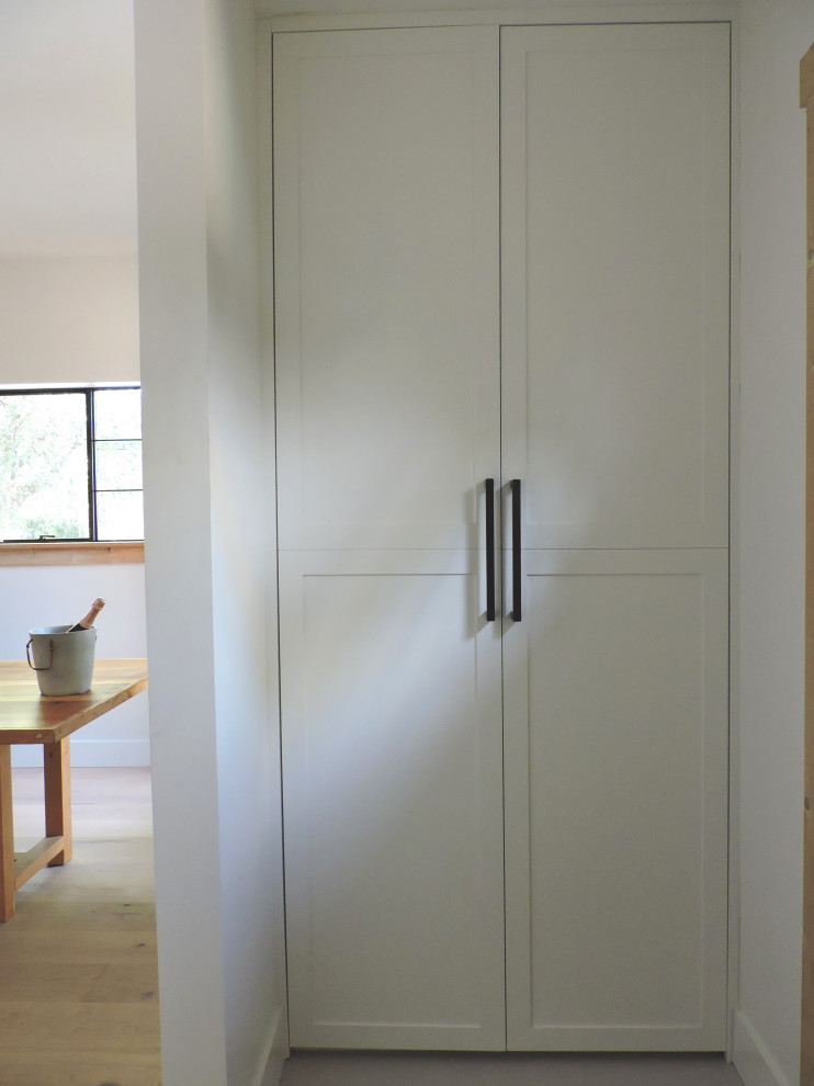 Imagen de armario y vestidor tradicional renovado pequeño con a medida, armarios estilo shaker, puertas de armario blancas y suelo de cemento