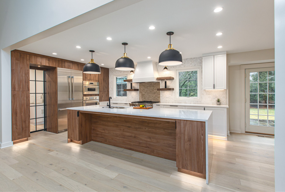 This is an example of a large transitional l-shaped eat-in kitchen in DC Metro with an undermount sink, shaker cabinets, white cabinets, quartz benchtops, beige splashback, ceramic splashback, stainless steel appliances, light hardwood floors, with island, white floor and white benchtop.