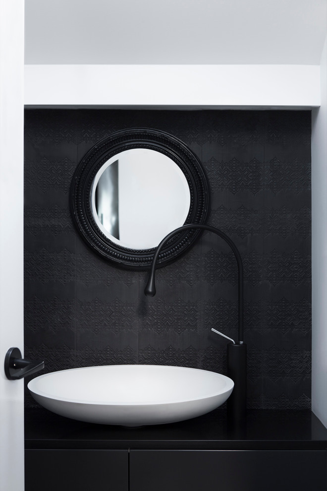 Small contemporary powder room in Melbourne with a vessel sink, flat-panel cabinets, black cabinets, granite benchtops, black tile, ceramic tile and white walls.
