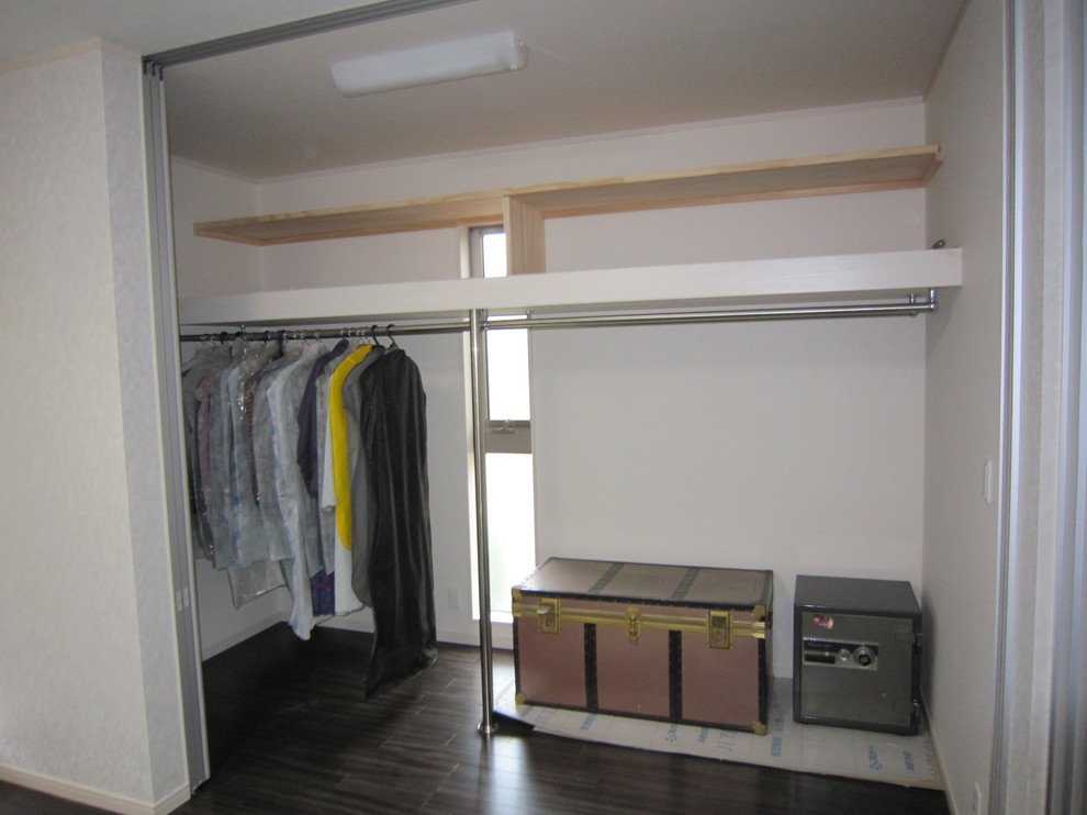 Large modern women's walk-in wardrobe in Other with plywood floors and brown floor.
