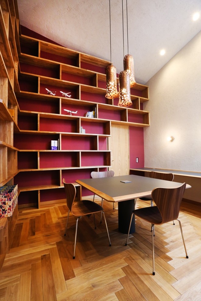 This is an example of a contemporary home office in Sapporo with white walls, medium hardwood floors, a freestanding desk and brown floor.
