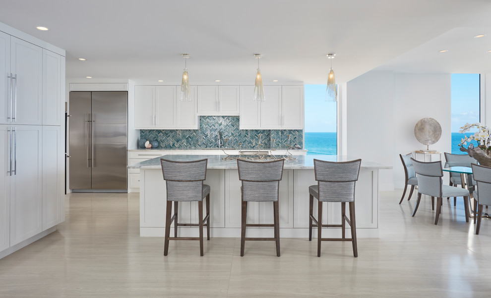 Inspiration for a large transitional single-wall open plan kitchen in Miami with a single-bowl sink, shaker cabinets, white cabinets, quartzite benchtops, blue splashback, glass tile splashback, stainless steel appliances, porcelain floors, with island and blue benchtop.
