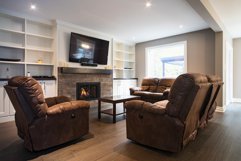 Design ideas for a mid-sized transitional open concept family room in Toronto with grey walls, medium hardwood floors, a standard fireplace, a brick fireplace surround, a wall-mounted tv and brown floor.
