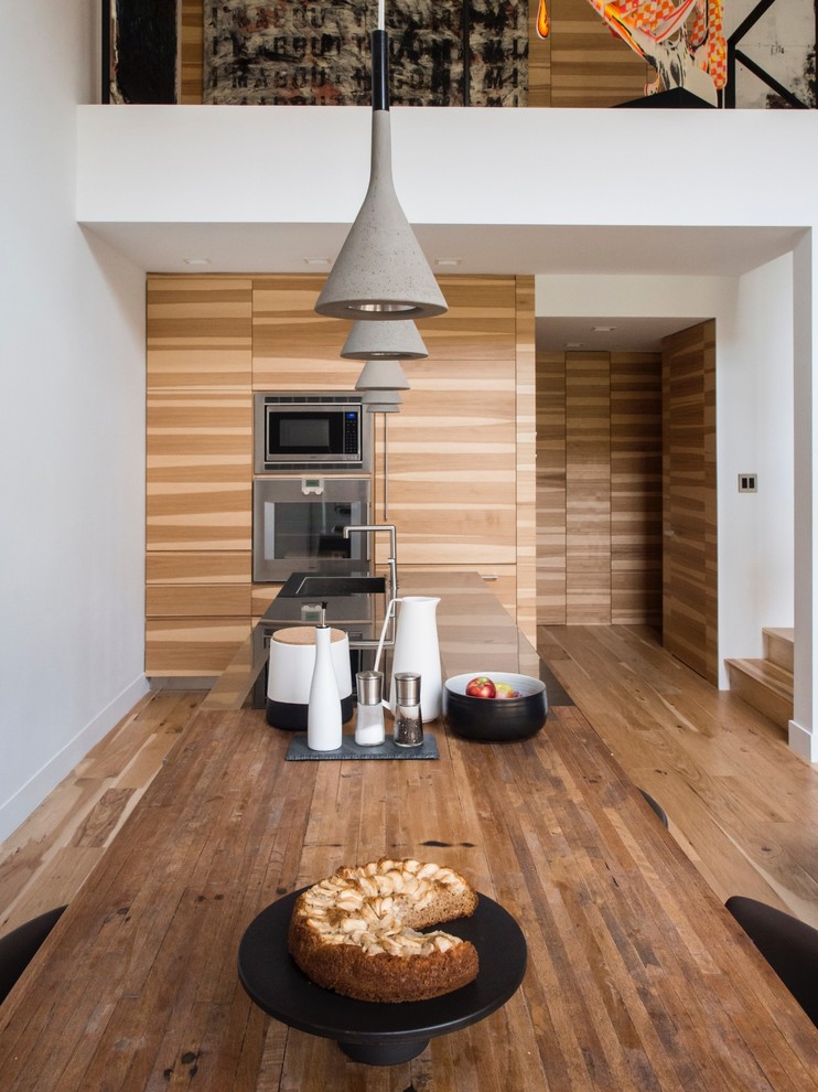 Inspiration for a contemporary open plan kitchen in Montreal with an integrated sink, flat-panel cabinets, medium wood cabinets, wood benchtops, panelled appliances, medium hardwood floors and with island.