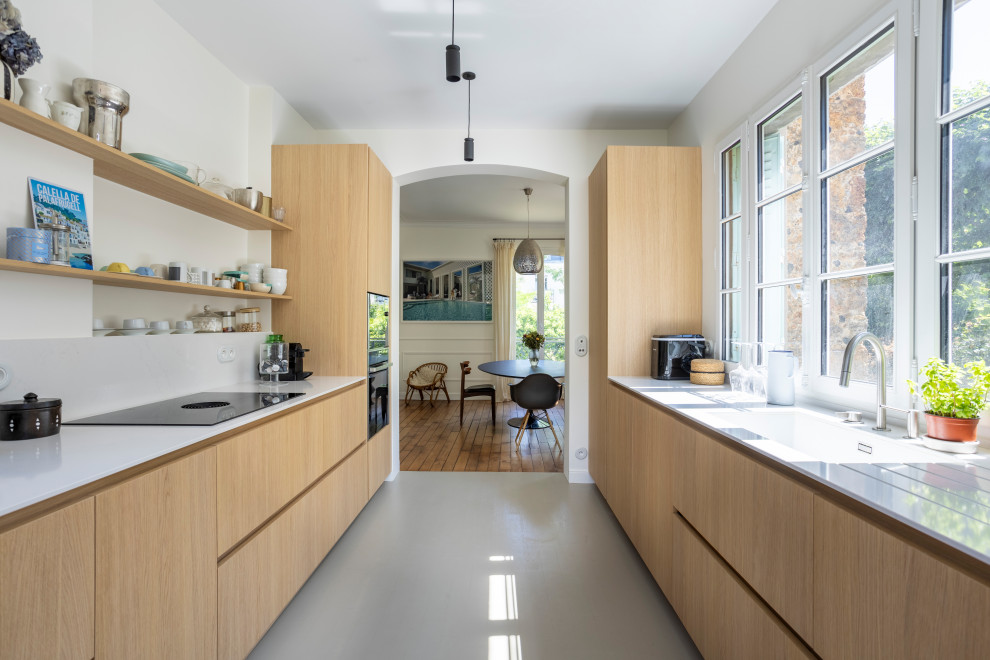 This is an example of a contemporary galley separate kitchen in Paris with light wood cabinets, quartzite benchtops, white splashback, engineered quartz splashback and white benchtop.