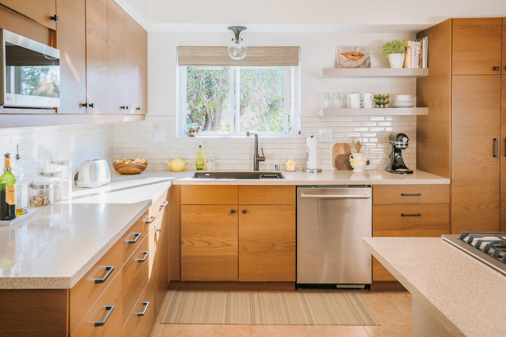 Photo of a midcentury l-shaped kitchen in San Diego with an undermount sink, flat-panel cabinets, medium wood cabinets, white splashback, subway tile splashback, stainless steel appliances, with island, beige floor and beige benchtop.