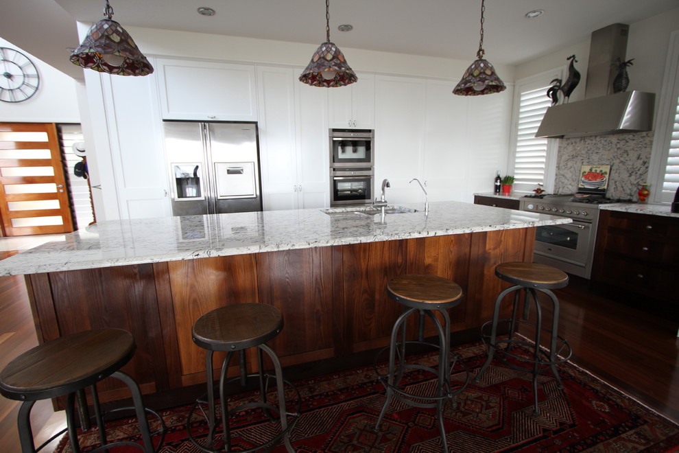 Photo of a mid-sized traditional eat-in kitchen in Brisbane with an undermount sink, shaker cabinets, granite benchtops, stone slab splashback, stainless steel appliances, dark hardwood floors and with island.