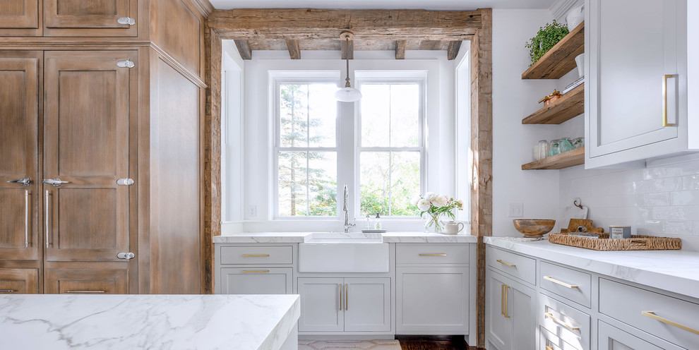 Design ideas for a large country l-shaped open plan kitchen in Boston with a farmhouse sink, shaker cabinets, medium wood cabinets, white splashback, panelled appliances, medium hardwood floors, with island, brown floor and white benchtop.