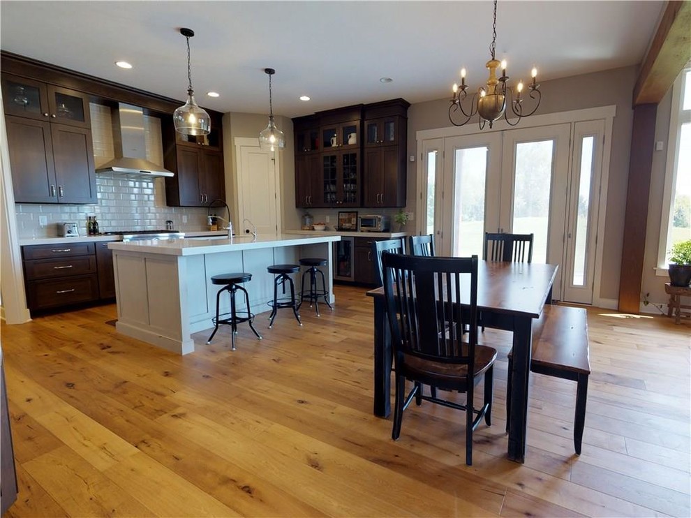 Inspiration for a transitional light wood floor eat-in kitchen remodel in Indianapolis with an undermount sink, flat-panel cabinets, medium tone wood cabinets, quartz countertops, white backsplash, subway tile backsplash, stainless steel appliances and an island