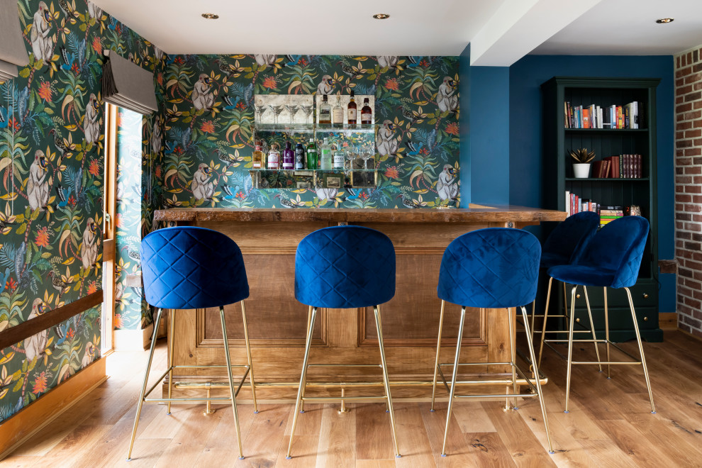 This is an example of a large eclectic l-shaped seated home bar in Cambridgeshire with medium hardwood floors, brown floor, wood benchtops and brown benchtop.