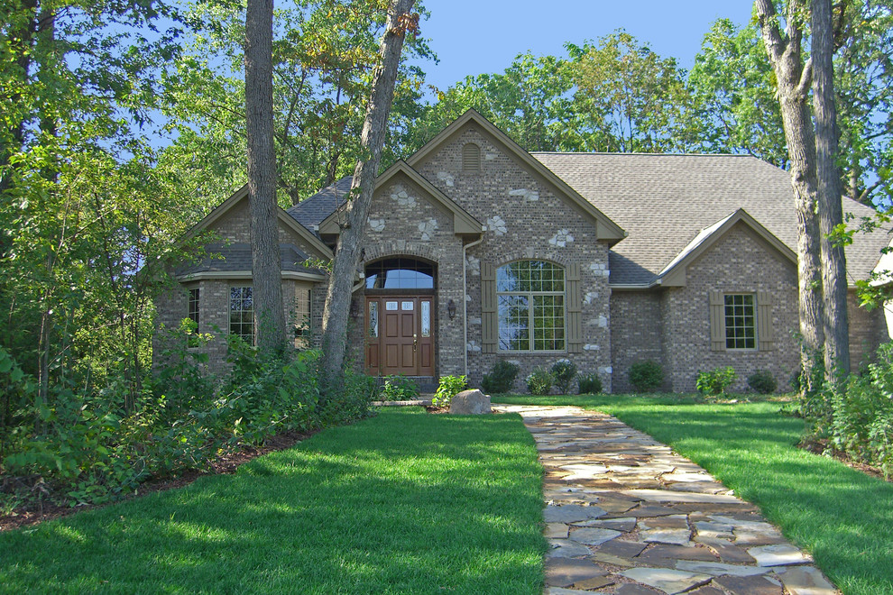 Large traditional brown one-story stone exterior home idea in Milwaukee with a shingle roof